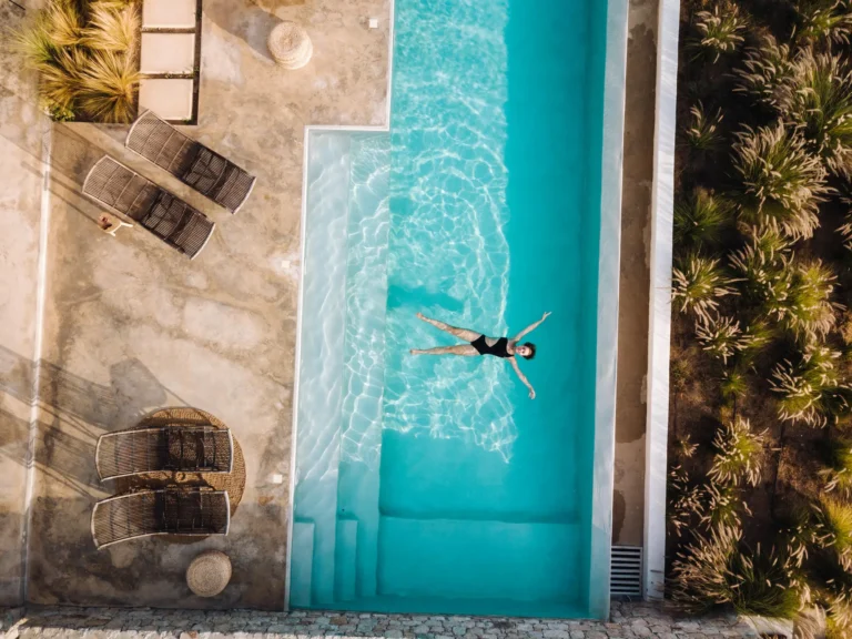 Aerial view of a woman relaxing in a swimming pool in her luxury villa in Mallorca villa; illustrating factors like pools and high-value structures that influence comprehensive property insurance costs in Mallorca.
