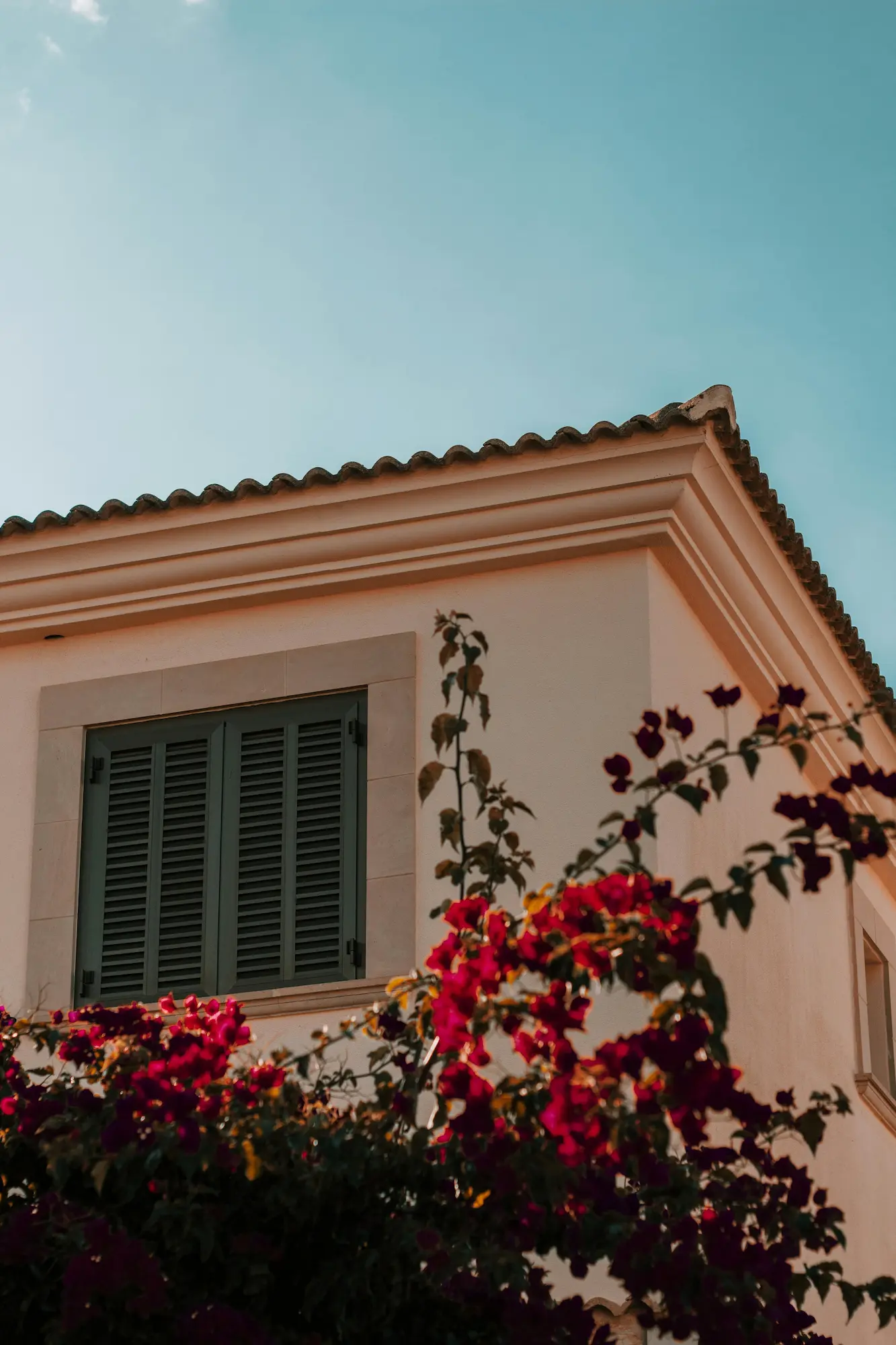 Wooden shutters of a large traditional Mallorca villa overlooking a sunny private garden.